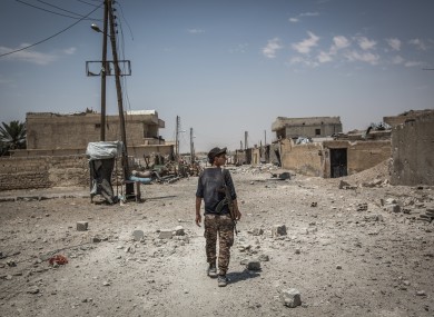 A soldier of the Syrian Democratic Forces (SDF) walks on a street in Al Sinaa neighborhood, eastern Raqqa.