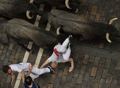 A reveller falls in front of Jose Escolar fighting bulls during the second running of the bulls at the San Fermin Festival.