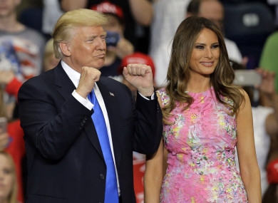 President Donald Trump pumps his fists as first lady Melania Trump watches crowd.