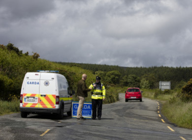 A garda stands at road block to the crime scene where the body parts were found.