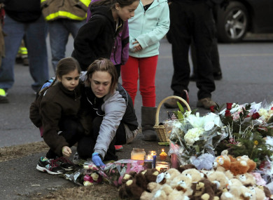 A woman and a little girl leave a bouquet of flowers at a makeshift memorial near Sandy Hook Elementary School in 2012.