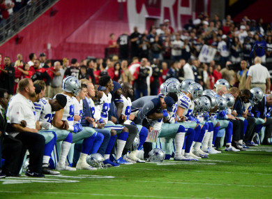 The Dallas Cowboys players, coaches and staff take a knee prior to the national anthem before the game against the Arizona Cardinals.