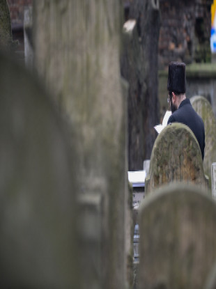 A jewish man prays next to a tomb in the Jewish cemetery in Krakow.