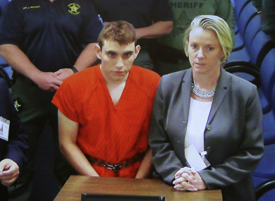 A video monitor shows school shooting suspect Nikolas Cruz, left, making an appearance before Judge Kim Theresa Mollica in Broward County Court.