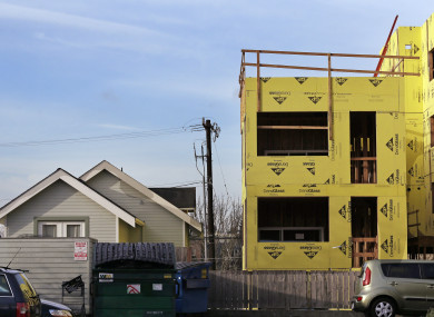 A four-storey mixed-use building is under construction adjacent to an older, single-family home in Seattle.