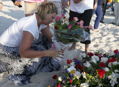 A tourist places places flowers at the scene of the attack in Sousse, Tunisia