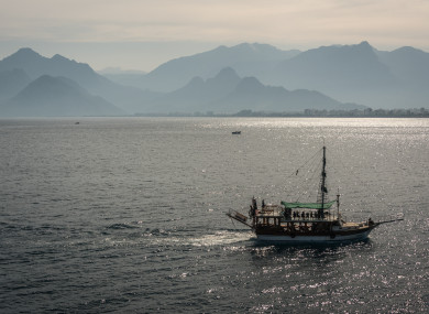 A tourist ship sails in front of a mountain landscape near Antalya, a major summer destination for tourism along Turkey's Mediterranean coast.
