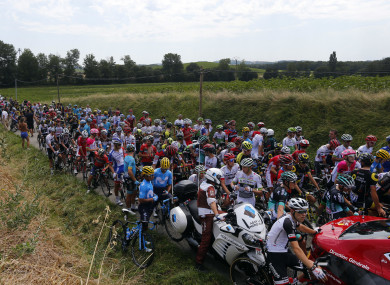 Riders wait on the road after a farmer's protest interrupted the 16th stage of the Tour de France.
