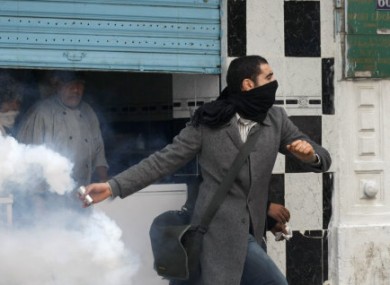A protestor throws back tear gas at the police during clashes after a demonstration against the Constitutional Democratic Rally, RCD, party of Ben Ali in the center of Tunis, Tuesday, Jan. 18. 2011.