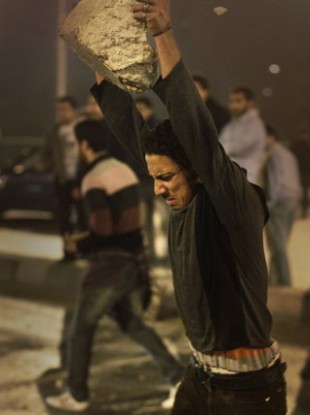 A protester throws a concrete block to the ground to break into smaller pieces to throw at riot police during clashes in downtown Cairo, Egypt, in the early hours of Wednesday, Jan. 26, 2011.