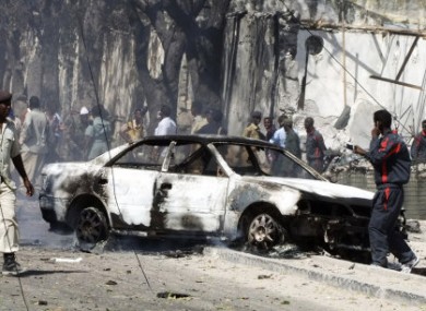 Somali police officers look at the wreckage of a car destroyed in a suicide bombing attack which targeted a police station in southern Mogadishu's Waberi district, Somalia, Monday, Feb. 21, 2011.