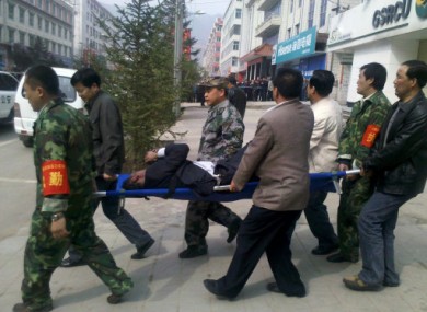 An injured person is removed from the bank in Tianzhu, China after a disgruntled former employee threw a gas bomb into the building