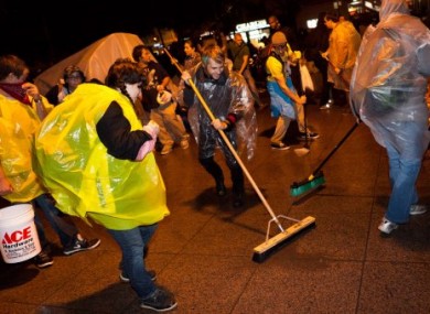 Demonstrators affiliated with the Occupy Wall Street protests sweep Zucotti park to preempt a scheduled cleanup by owners Friday morning that protestors say is a move to shut them down, Friday, Oct. 14, 2011