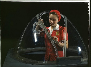 This girl in a glass house is putting finishing touches on the bombardier nose section of a B-17F navy bomber at Long Beach in California.