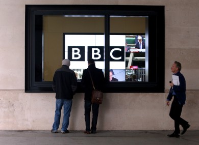 Staff walk past television screens at the BBC's Headquarters, New Broadcasting House, in central London.