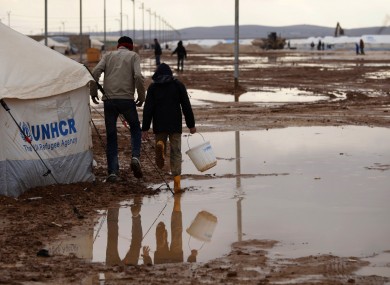 Syrian refugees walk on water and mud, at Zaatari Syrian refugee camp, near the Syrian border in Mafraq, Jordan.
