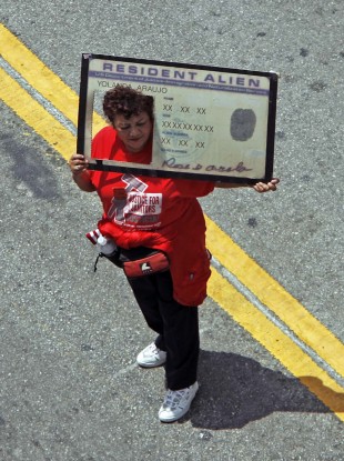 A protester holding a banner that looks like a United States green card attends a rally for immigration reform.