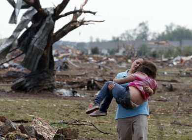 A woman carries a child through a field near the collapsed Plaza Towers Elementary School in Moore