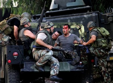 Lebanese army soldiers help injured soldiers after clashes between followers of a radical Sunni cleric Sheik Ahmad al-Assir and Shiite gunmen, in the southern port city of Sidon, Lebanon today.