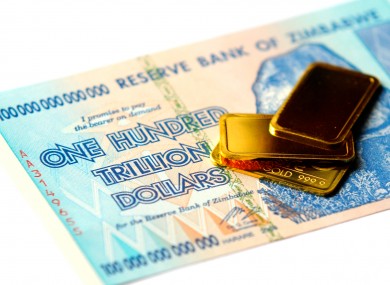 A Zimbabwe One Hundred Trillion Dollar note and small gold bars
