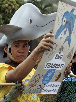 An animal rights advocate, wearing a dolphin hat, displays a placard during a picket at the Japanese Embassy in Manila, Philippines