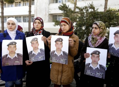Anwar al-Tarawneh, center, the wife of the Jordanian pilot holds a poster of him, with Arabic that reads,