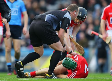 Referee Alan Kelly and Cork defender Shane O'Neill check on the injured Christopher Joyce.