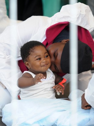 A migrant kisses a baby after they disembarked from the Italian Navy vessel 'Bettica' in the harbour of Salerno, Italy. About 700 migrants were rescued in the Sicilian Strait while they were trying to cross.