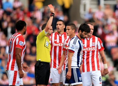 Michael Oliver (left) gives a red card to Stoke City's Ibrahim Afellay.
