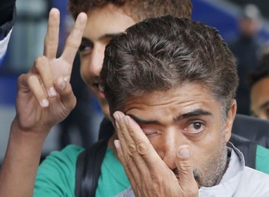 Refugees flash victory signs and wipe away tears as they arrive at the main train station in Munich.