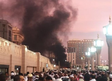 People stand by an explosion site in Medina