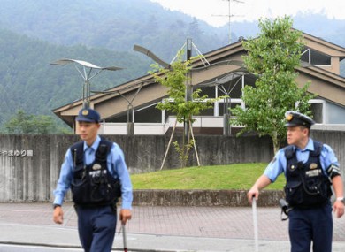 Police officers stand guard a facility for the disabled where a number of people were killed and dozens injured in a knife attack.