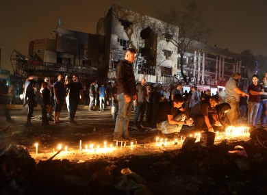 People light candles at the scene of a massive car bomb attack in Karada
