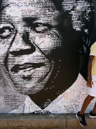 A young boy stands in front of a poster of former South African president Nelson Mandela.