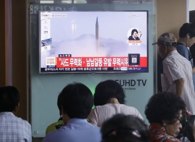 A man passes by a TV news program with a file footage about North Korea's rocket launch yesterday.