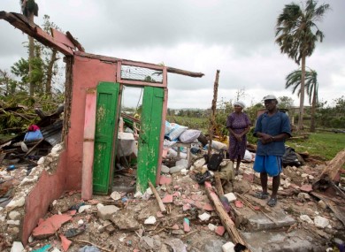 Saintanor Dutervil stands with his wife in the ruins of their home destroyed by Hurricane Matthew in Haiti.