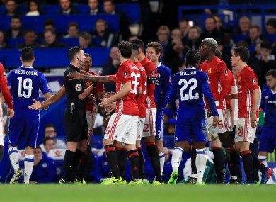 Man United players crowd around referee Michael Oliver.