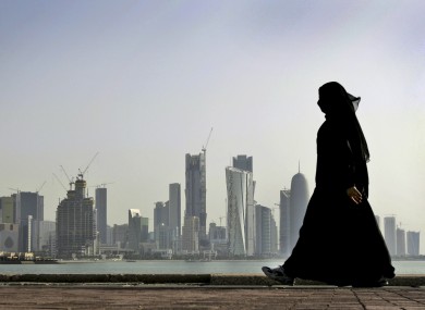 A Qatari woman walks in front of Doha, the capital city of Qatar.