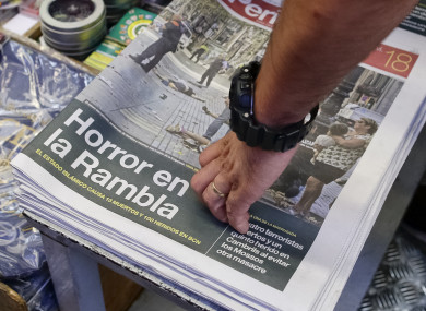 A man touches a newspaper displaying a photograph of the aftermath of the terror attack on Las Ramblas.