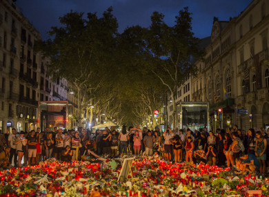 People standing next to candles and flowers placed on the ground after the terror attack.