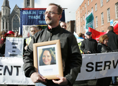 Conor Mac Liam holds a picture of his wife Susie Long at a demonstration in Dublin.