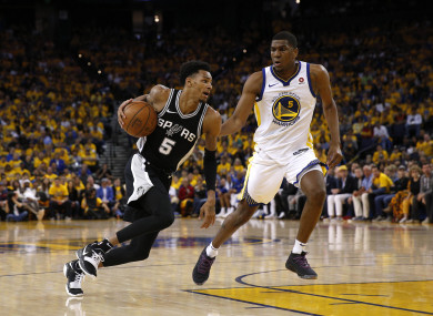 Dejounte Murray dribbles past Golden State Warriors forward Kevon Looney.