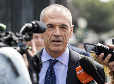 Economist Carlo Cottarelli is surrounded by reporters as he arrives at Rome's Termini train station yesterday.