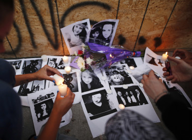 People light candles and leave photos of 18-year-old victim Reese Fallon at a memorial remembering the victims of a shooting on Sunday evening