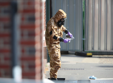 An investigator in a chemical suit removes an item as they work behind screens erected in Rollestone Street, Salisbury
