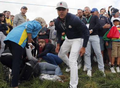 Brooks Koepka of the US offers a golf glove to a spectator he injured when his ball hit her on the 6th hole during his fourball match on the opening day of the 42nd Ryder Cup.