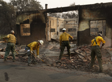 Fire crews clear rubble from the road near a building in Paradise, California.