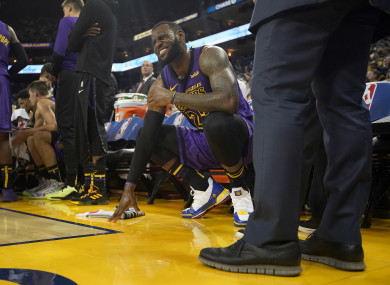 LeBron James grimaces after straining his left groin, during the second half of their game against the Warriors.