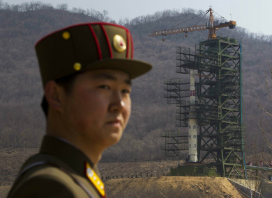 File photo - A North Korean soldier stands in front of the country's Unha-3 rocket