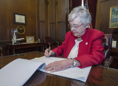 This photograph released by the state shows Alabama Governor Kay Ivey signing a bill that virtually outlaws abortion in the state